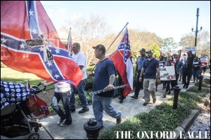 A man carrying a Mississippi state flag is followed by those calling on the University of Mississippi to remove the Mississippi state flag from university grounds, in Oxford, Miss. on Friday, October 16, 2015.